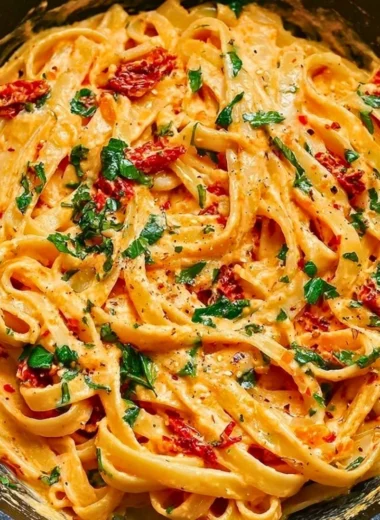 Creamy vegan sun-dried tomato pasta dish garnished with fresh herbs