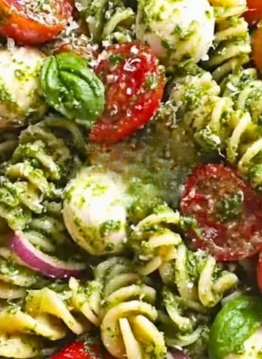 Pesto pasta salad with tomatoes and mozzarella in a bowl.