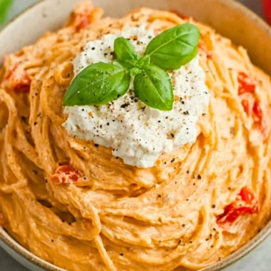 Plate of roasted tomato and garlic ricotta pasta garnished with basil