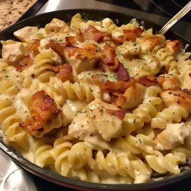 A bowl of Chicken Bacon Ranch Pasta topped with parsley and crispy bacon.