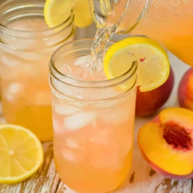 A refreshing glass of homemade peach lemonade garnished with fresh peach slices and mint.