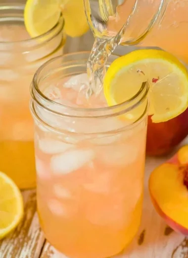 A refreshing glass of homemade peach lemonade garnished with fresh peach slices and mint.