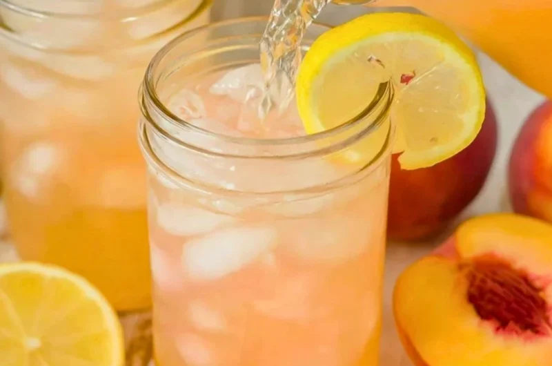 A refreshing glass of homemade peach lemonade garnished with fresh peach slices and mint.