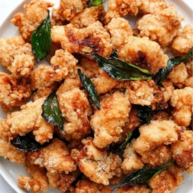 Plate of crispy Taiwanese popcorn chicken with seasonings and herbs