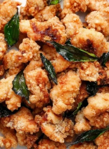 Plate of crispy Taiwanese popcorn chicken with seasonings and herbs