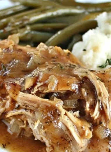 Crock Pot Mississippi Chicken served with sides on a rustic plate.