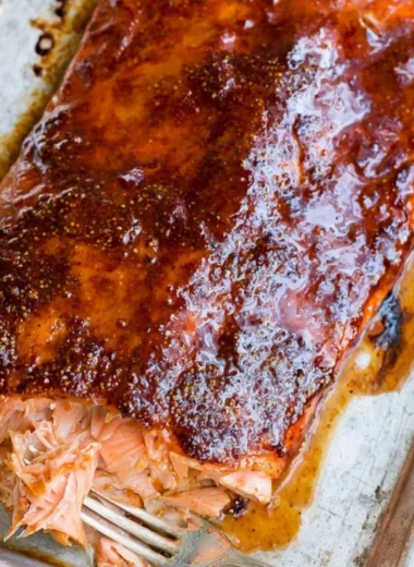 Delicious and easy five ingredient baked salmon on a plate garnished with herbs