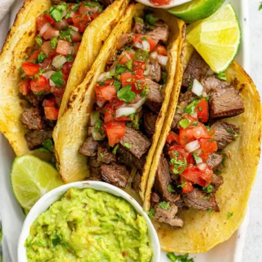 Delicious grilled beef tacos with fresh toppings on a wooden table