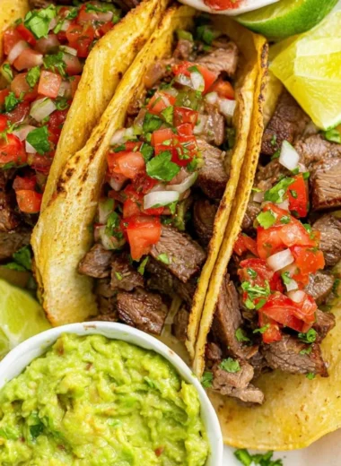 Delicious grilled beef tacos with fresh toppings on a wooden table