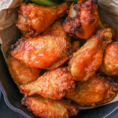 Homemade buffalo wings with spicy sauce and garnishes on a platter