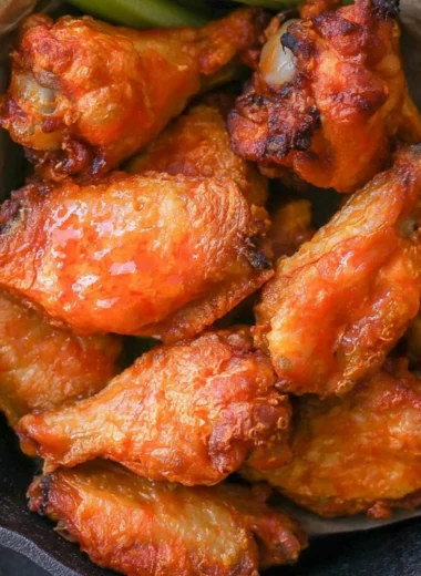 Homemade buffalo wings with spicy sauce and garnishes on a platter