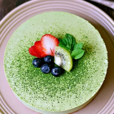 No-bake Matcha Cheesecake slice on a plate with green tea leaves
