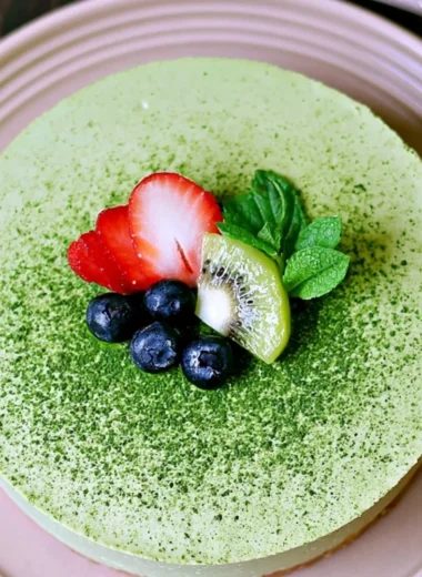 No-bake Matcha Cheesecake slice on a plate with green tea leaves