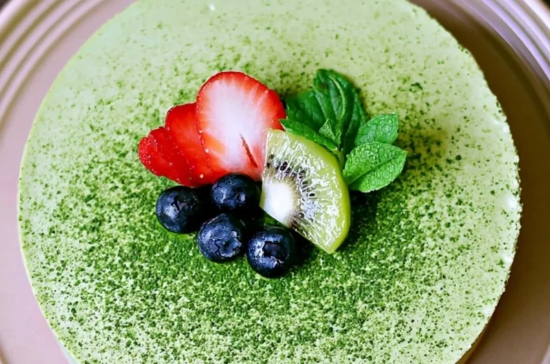 No-bake Matcha Cheesecake slice on a plate with green tea leaves