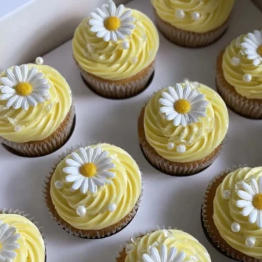 Pastel yellow cupcakes decorated with daisies and pearls