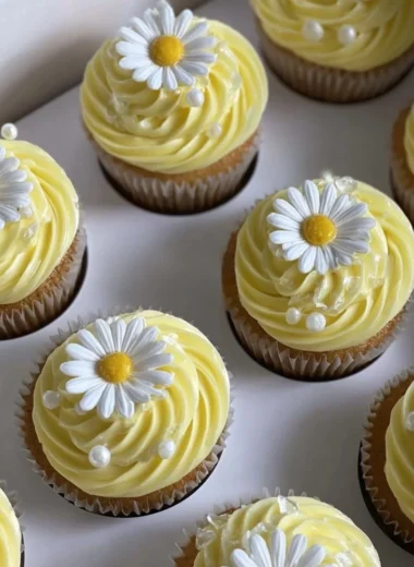 Pastel yellow cupcakes decorated with daisies and pearls