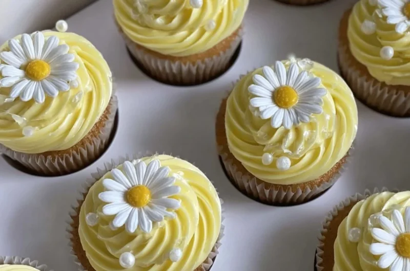 Pastel yellow cupcakes decorated with daisies and pearls