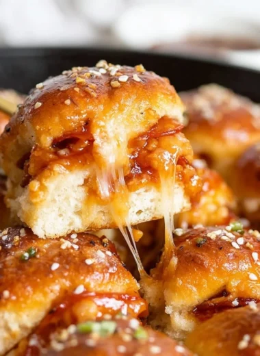 Delicious pizza sliders topped with cheese and pepperoni on a rustic serving board.