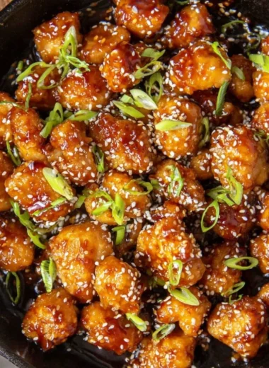 Delicious bowl of Sesame Chicken with sesame seeds and green onions
