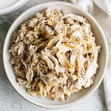 A plate of tender shredded chicken served with spices and herbs.