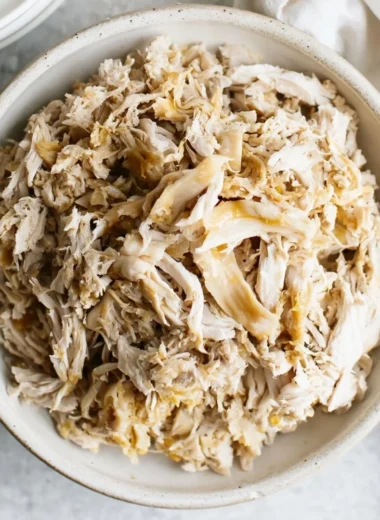 A plate of tender shredded chicken served with spices and herbs.