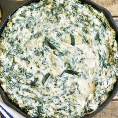 Creamy spinach artichoke dip served in a bowl with fresh vegetables