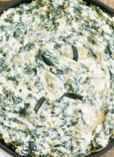 Creamy spinach artichoke dip served in a bowl with fresh vegetables