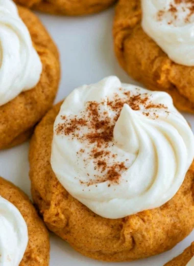 Delicious pumpkin cookies with cream cheese frosting on a wooden table
