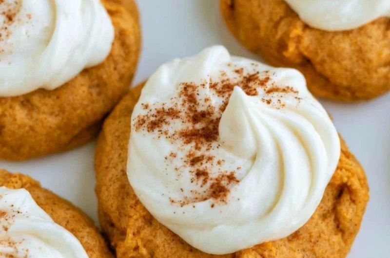 Delicious pumpkin cookies with cream cheese frosting on a wooden table
