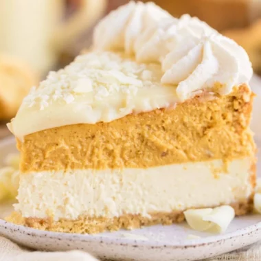 Delicious Eggnog Pumpkin Cheesecake topped with whipped cream and spices