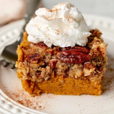 Delicious Pumpkin Dump Cake served with whipped cream on a plate