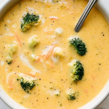 Bowl of creamy broccoli cheddar soup garnished with fresh broccoli and cheese