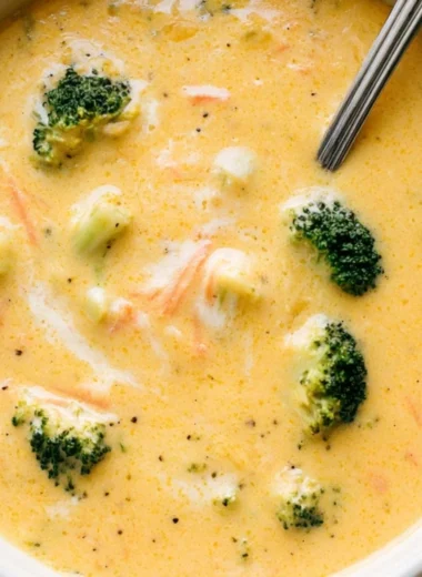 Bowl of creamy broccoli cheddar soup garnished with fresh broccoli and cheese